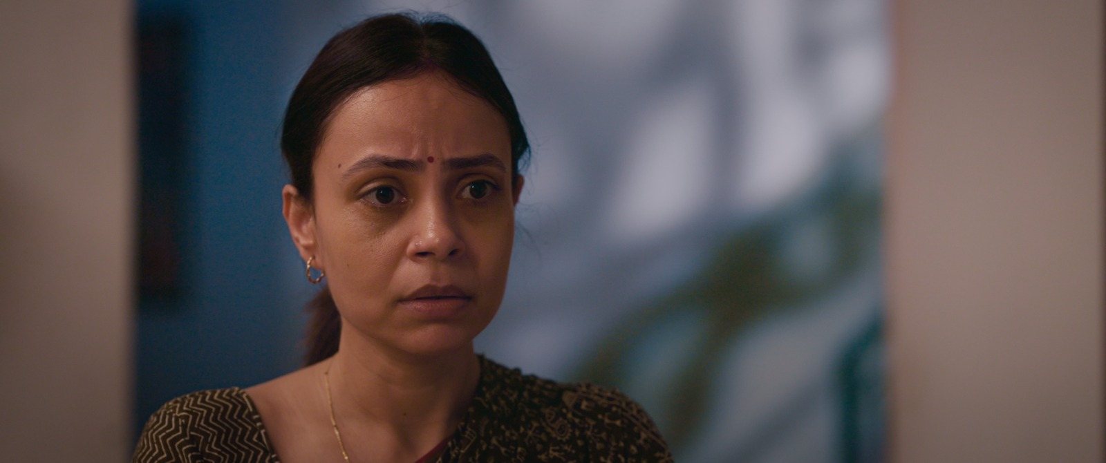 Close-up of Kavita's face, her expression caught between worry and resolve.